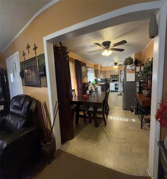 dining room with light floors, ceiling fan, ornamental molding, and a textured ceiling