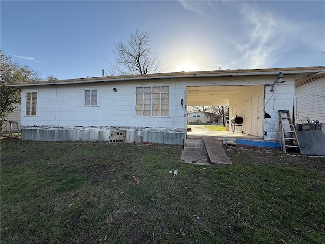 rear view of house featuring a carport and a lawn