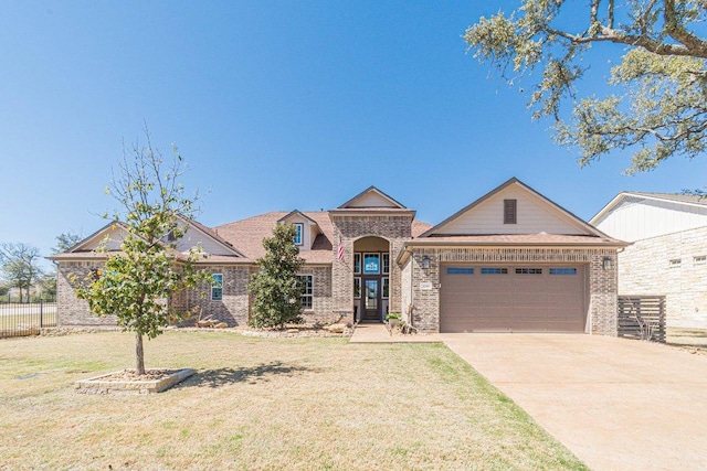 view of front of property with concrete driveway, an attached garage, fence, a front lawn, and brick siding