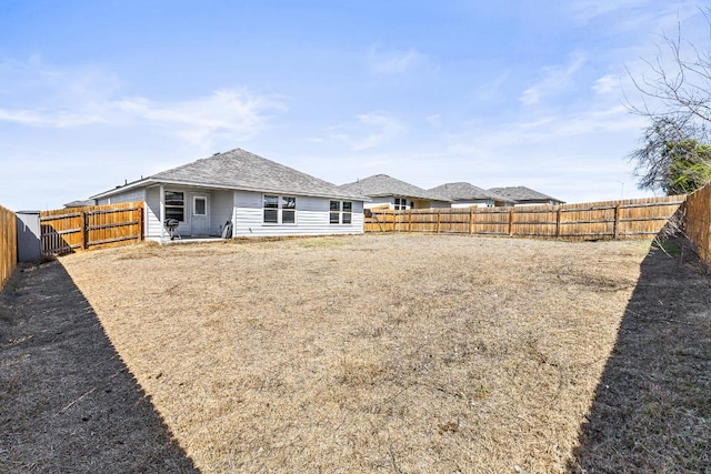 back of property featuring a shingled roof and a fenced backyard