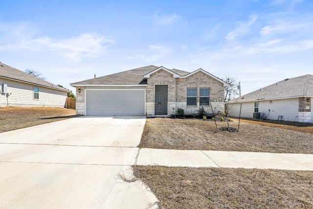 view of front of property with brick siding, central AC, a garage, stone siding, and driveway