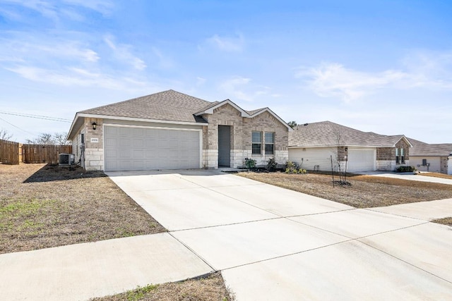 single story home featuring an attached garage, central air condition unit, a shingled roof, fence, and concrete driveway