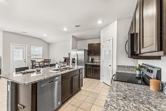 kitchen featuring dark brown cabinetry, stainless steel appliances, a sink, visible vents, and a center island with sink