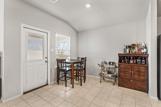 dining room featuring lofted ceiling, light tile patterned floors, and baseboards