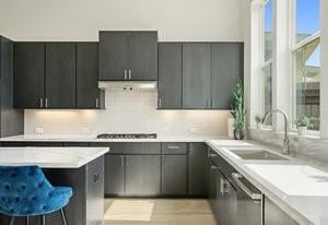 kitchen with a sink, extractor fan, light countertops, and stovetop