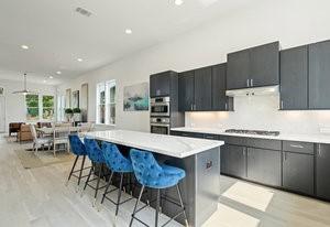 kitchen with a breakfast bar area, light countertops, double oven, a kitchen island, and stovetop