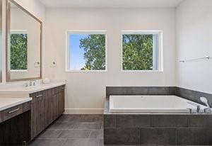 bathroom with vanity, a bath, and baseboards