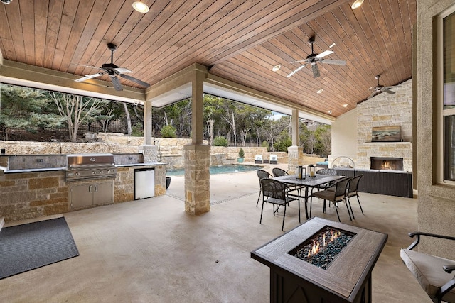 view of patio with area for grilling, a fenced in pool, an outdoor fire pit, and an outdoor stone fireplace