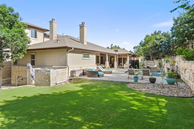 back of property with stucco siding, stone siding, a fenced backyard, a yard, and a patio area