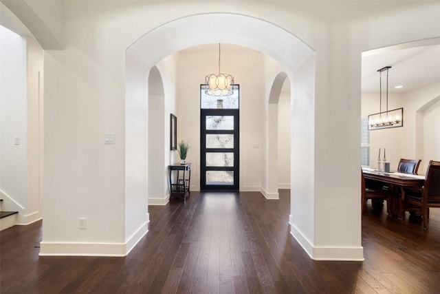 foyer featuring stairs, baseboards, a notable chandelier, and dark wood-style flooring