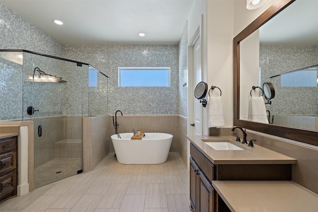 full bath with a soaking tub, a shower stall, vanity, and tile walls