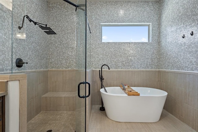 full bath with a shower stall, a soaking tub, and tile walls