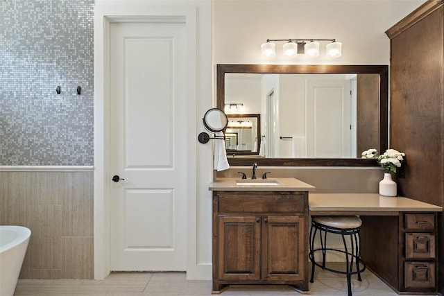 bathroom with a freestanding tub, vanity, and tile patterned flooring