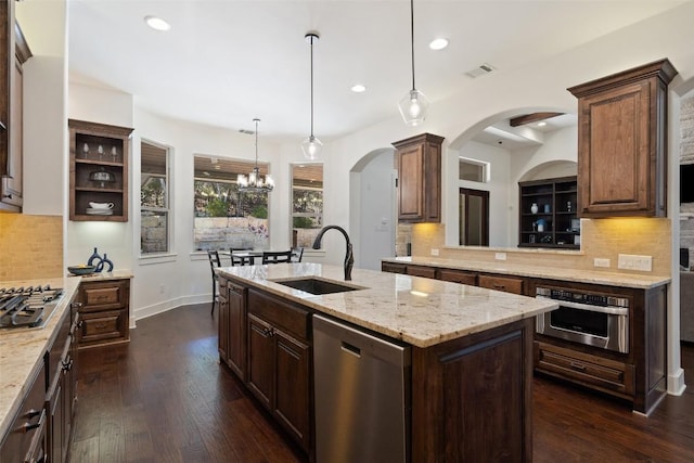 kitchen with visible vents, a center island with sink, a sink, dark wood-style floors, and appliances with stainless steel finishes