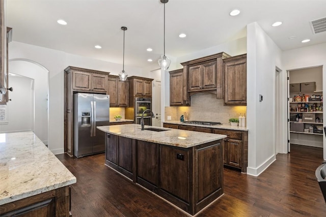 kitchen featuring visible vents, dark wood-type flooring, a sink, stainless steel appliances, and arched walkways