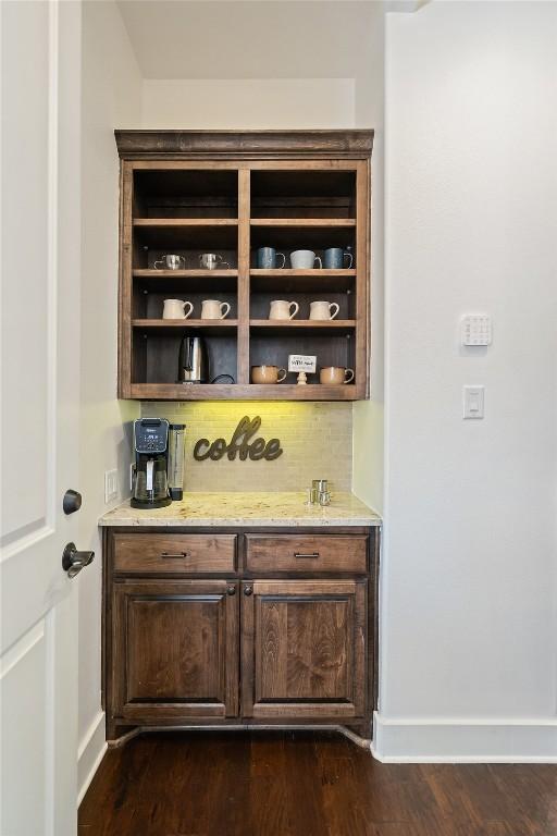 bar with backsplash, baseboards, and dark wood-style flooring