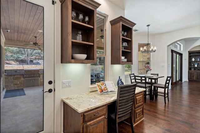 office featuring visible vents, ceiling fan with notable chandelier, dark wood finished floors, arched walkways, and built in study area