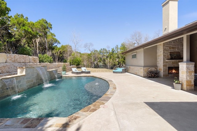 view of pool with a fenced in pool, an outdoor stone fireplace, and a patio area