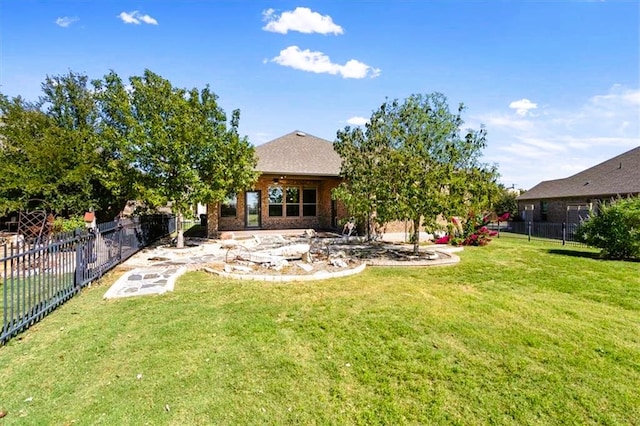 rear view of property with brick siding, fence, and a yard