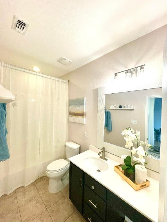 full bath with toilet, vanity, visible vents, tile patterned floors, and shower / bath combo