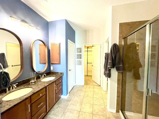 bathroom featuring a shower stall, double vanity, a sink, and tile patterned floors