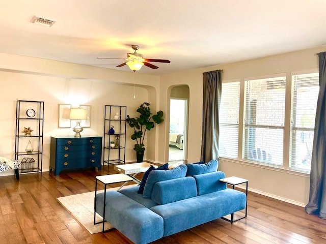 living room featuring plenty of natural light, visible vents, arched walkways, and dark wood-style flooring