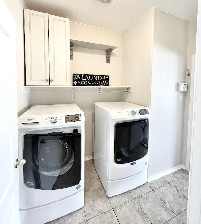 clothes washing area featuring cabinet space, light tile patterned floors, baseboards, and separate washer and dryer