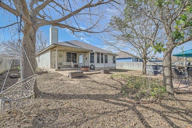 rear view of house featuring a fenced backyard, a patio, and a chimney