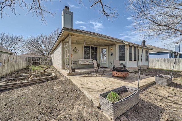 rear view of house with a patio area, a garden, a chimney, and a fire pit