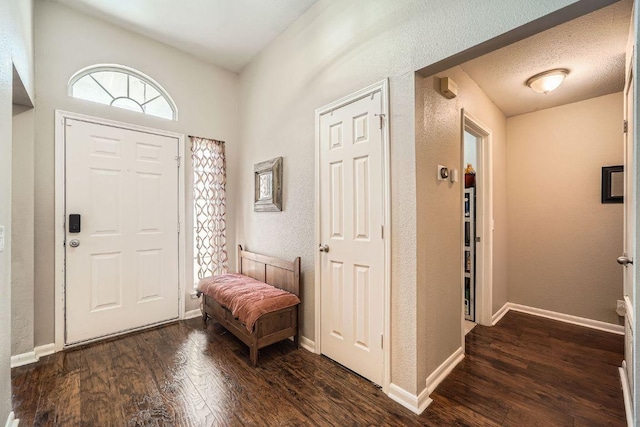 entrance foyer with dark wood-style floors, baseboards, a textured ceiling, and a textured wall