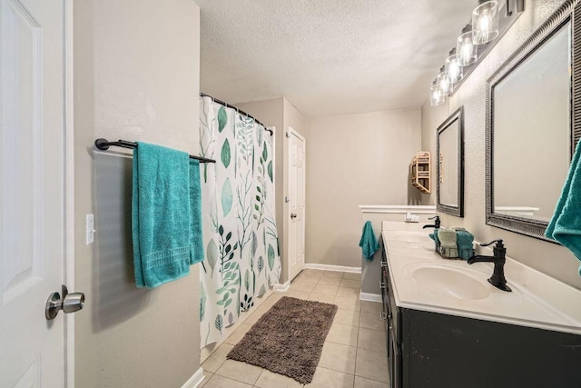 bathroom with a textured ceiling, tile patterned flooring, and a sink