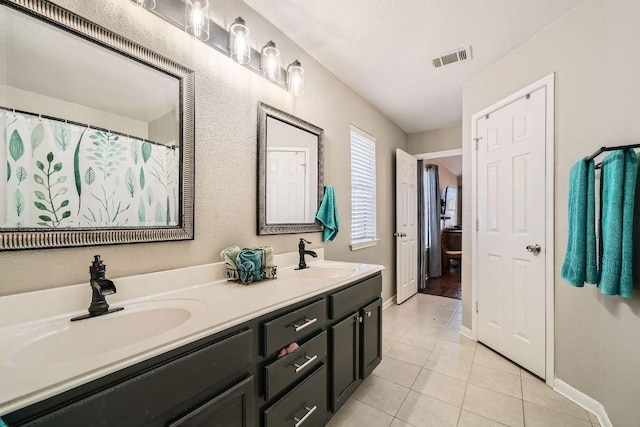 bathroom featuring tile patterned flooring, visible vents, a sink, and double vanity