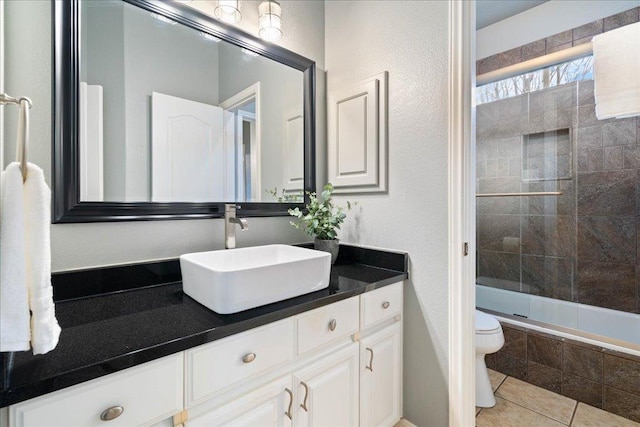 bathroom with tiled shower / bath combo, tile patterned flooring, vanity, and toilet