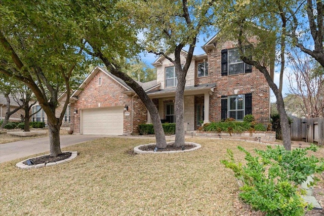 traditional-style house with brick siding, concrete driveway, an attached garage, fence, and a front yard