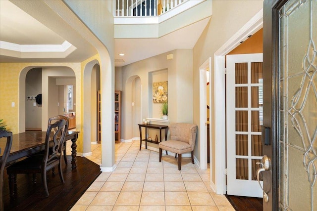 entrance foyer with arched walkways, recessed lighting, baseboards, and light tile patterned floors