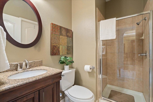 full bath featuring toilet, a shower stall, and vanity