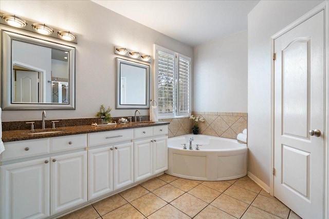 full bath with a garden tub, double vanity, a sink, and tile patterned floors