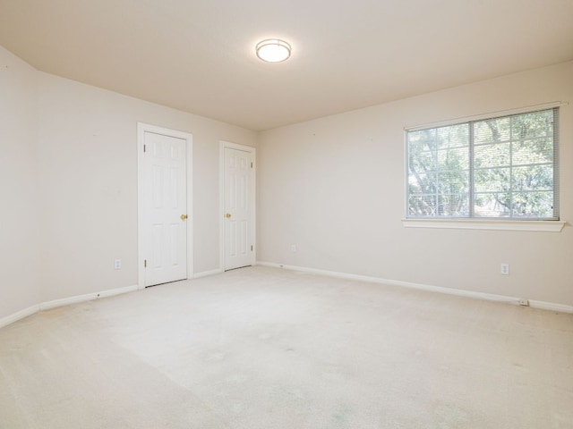 empty room featuring light colored carpet and baseboards