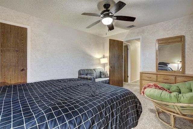 bedroom with a textured ceiling, carpet, visible vents, and a ceiling fan