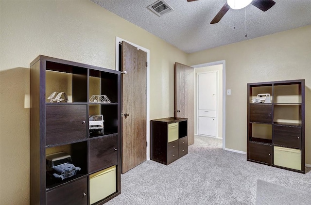 carpeted bedroom with a textured ceiling, baseboards, visible vents, and a ceiling fan