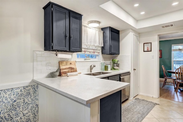 kitchen with dishwasher, tasteful backsplash, dark cabinetry, and a sink