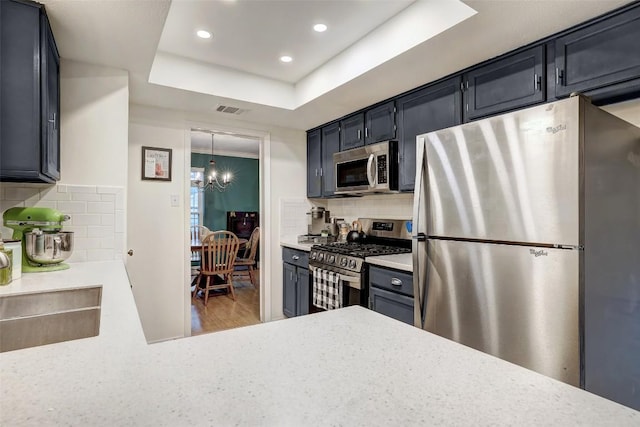 kitchen with appliances with stainless steel finishes, a raised ceiling, visible vents, and tasteful backsplash