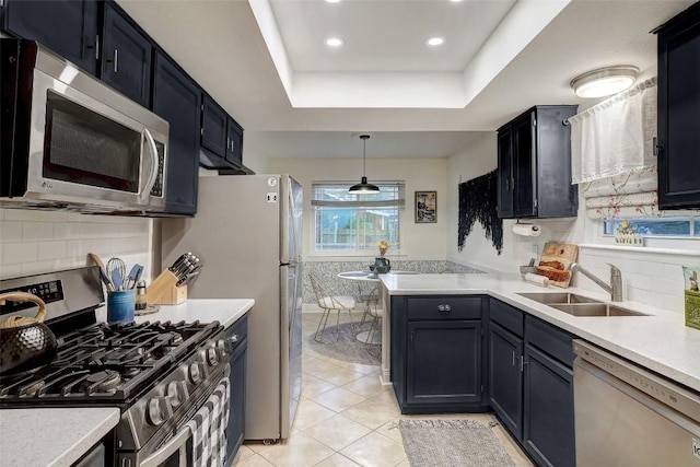 kitchen with a tray ceiling, stainless steel appliances, light countertops, a sink, and light tile patterned flooring