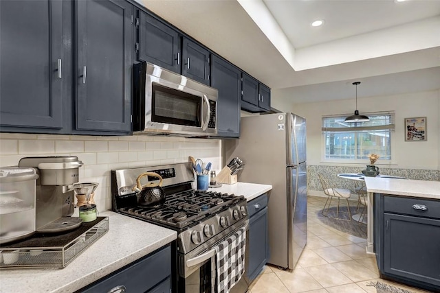 kitchen featuring appliances with stainless steel finishes, hanging light fixtures, blue cabinets, light countertops, and light tile patterned flooring