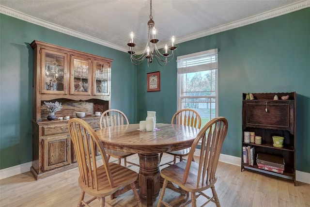 dining area featuring baseboards, a notable chandelier, light wood-style flooring, and crown molding