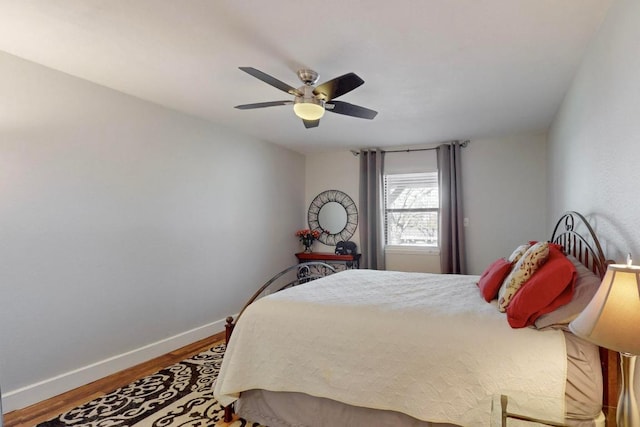 bedroom with a ceiling fan, baseboards, and wood finished floors