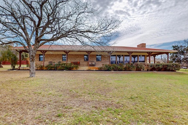 view of front facade with brick siding, a front yard, and a chimney