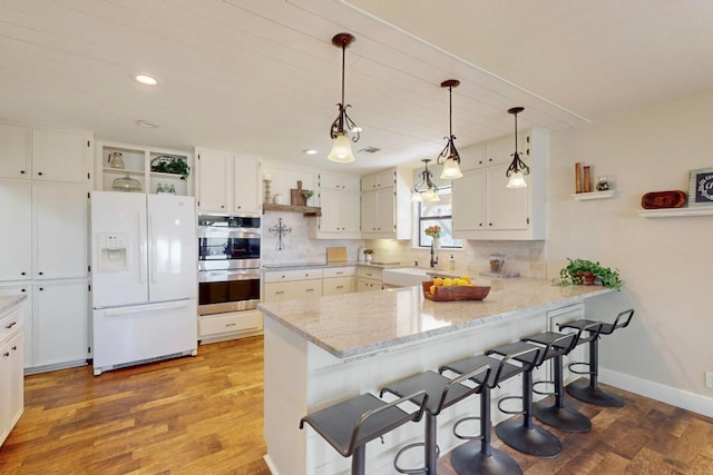 kitchen with open shelves, white refrigerator with ice dispenser, white cabinetry, stainless steel double oven, and a peninsula