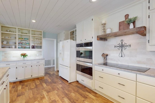 kitchen with double oven, open shelves, black electric cooktop, and white fridge with ice dispenser