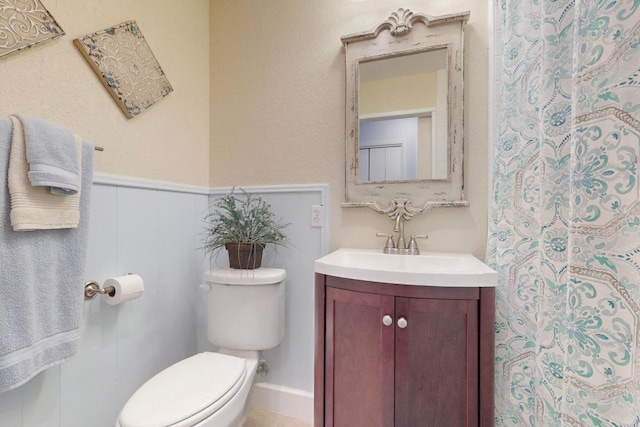 full bathroom with a shower with shower curtain, vanity, toilet, and wainscoting